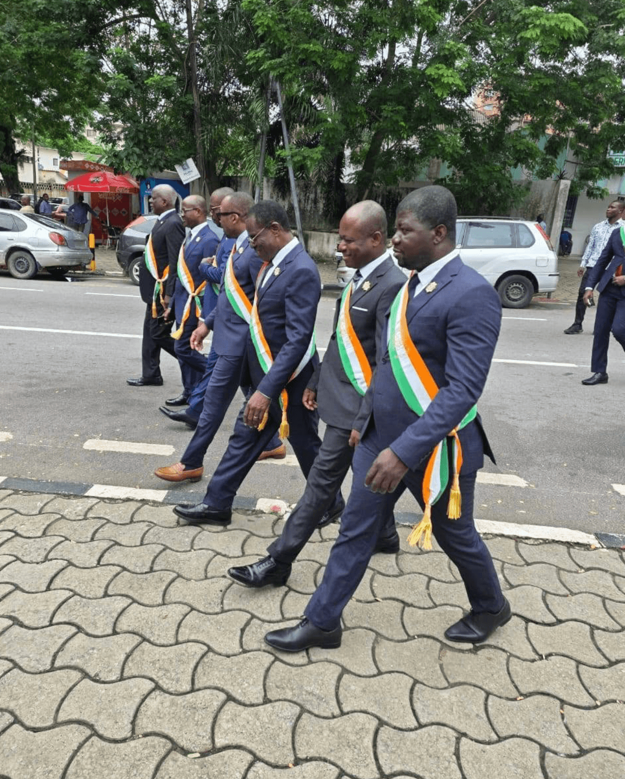 Députés portant l'écharpe tricolore défilant dans une rue.