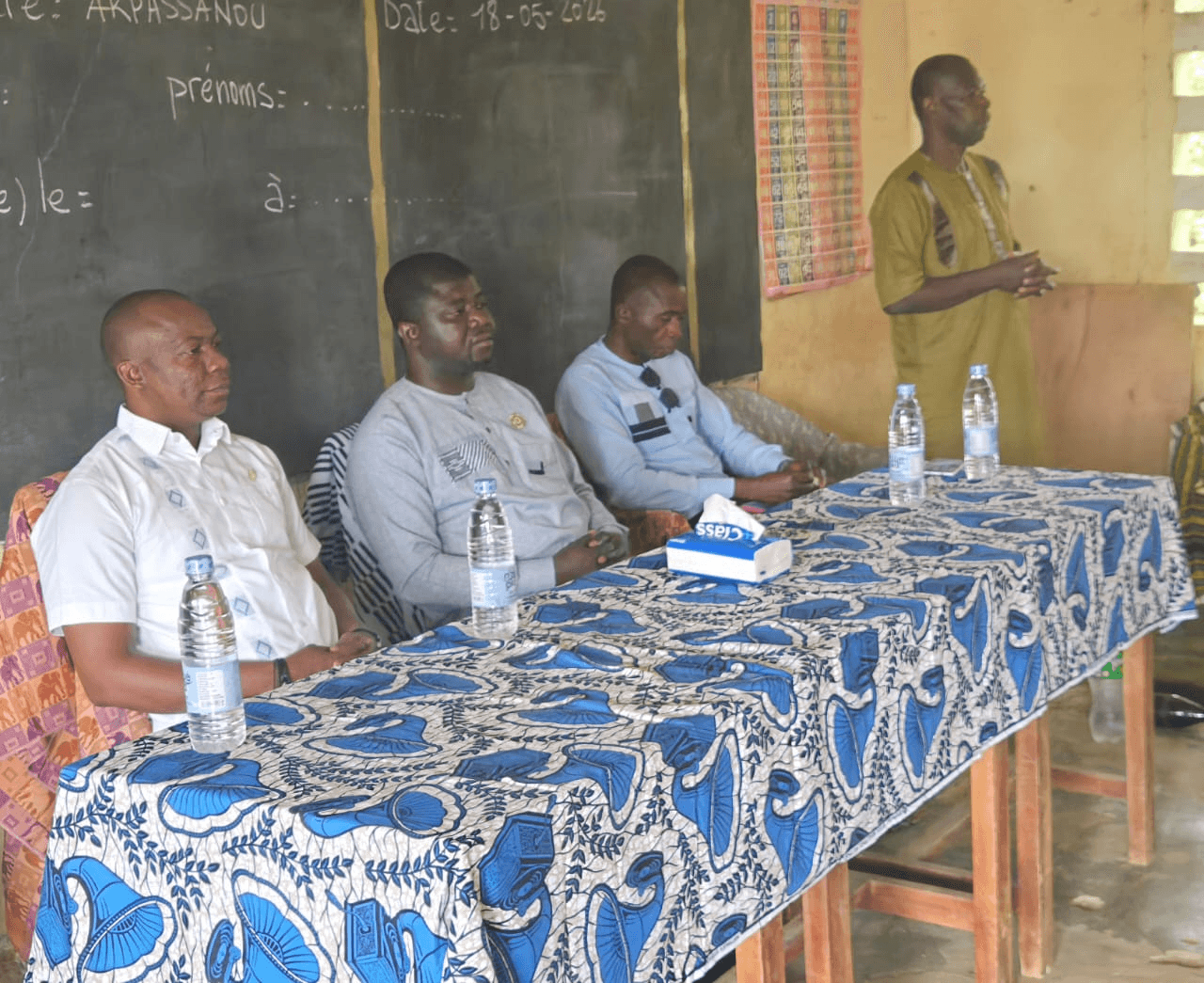 L'Honorable Innocent Yao et ses collaborateurs assis à la table de séance devant un tableau d'école portant la mention Akpassanou 18-05-2026.