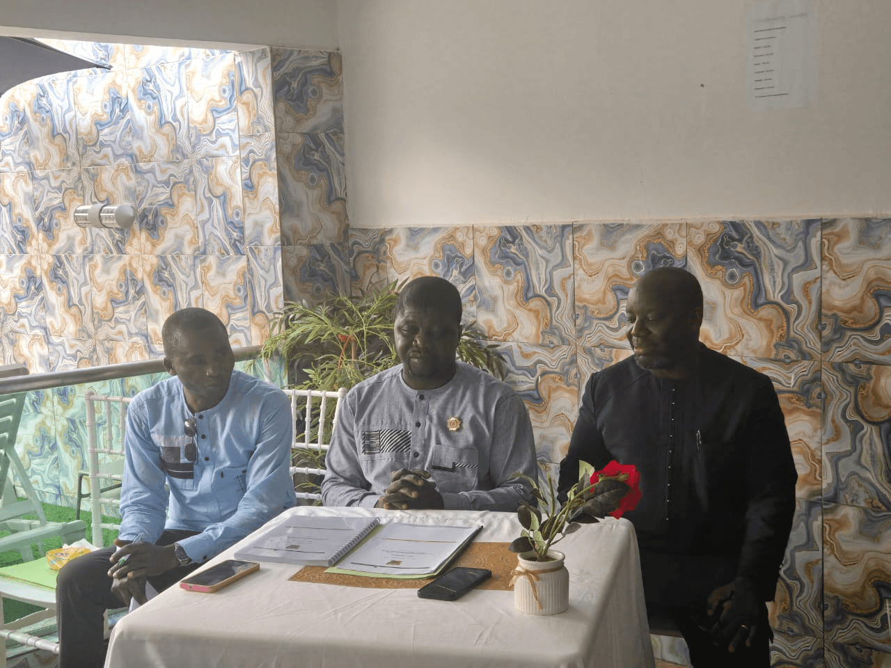L'Honorable Innocent Yao assis au centre d'une table couverte d'une nappe blanche avec des dossiers reliés.