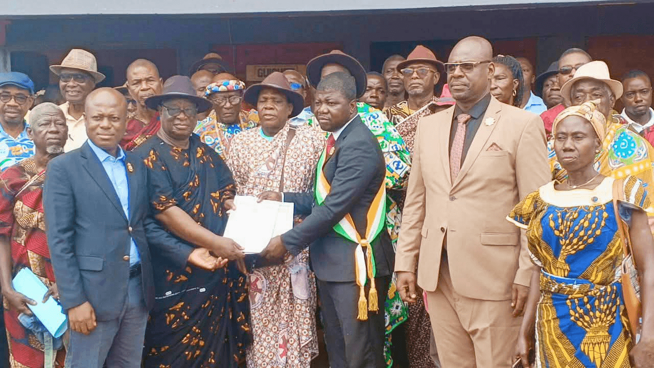 L'Honorable Innocent Yao remettant un document officiel aux chefs traditionnels en tenue d'apparat.