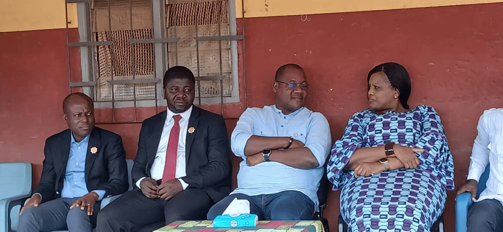 L'Honorable Innocent Yao et plusieurs personnalités assis en rangée sous un préau.
