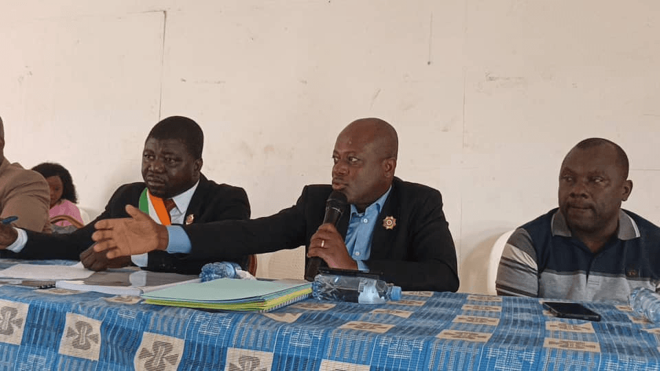 Intervenant au micro assis à la tribune à côté de l'Honorable Innocent Yao.