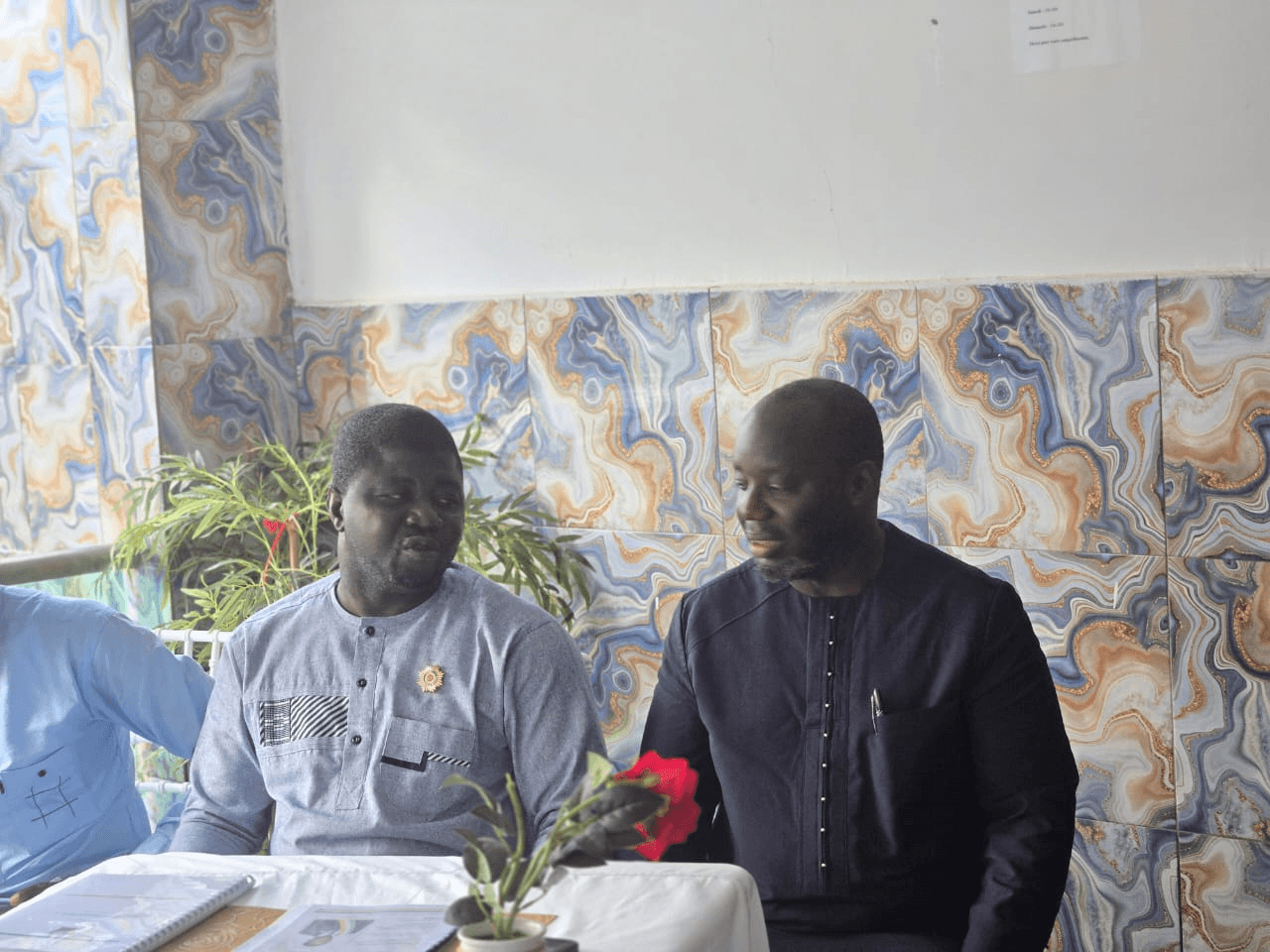 L'Honorable Innocent Yao discutant avec un collaborateur assis à ses côtés.